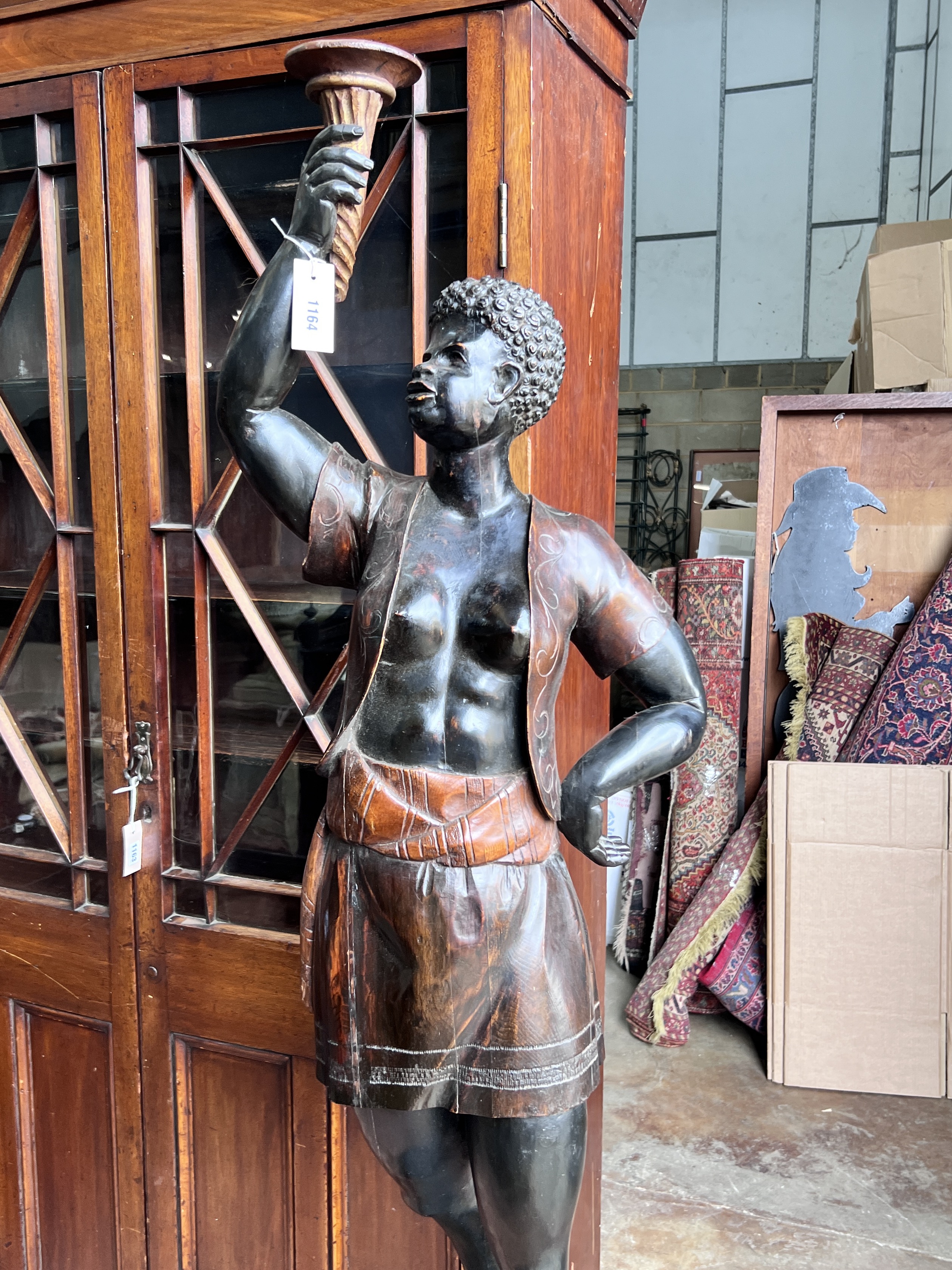 An early 20th century carved wood Blackamoor on associated hexagonal lion mask swagged plinth, height 193cm